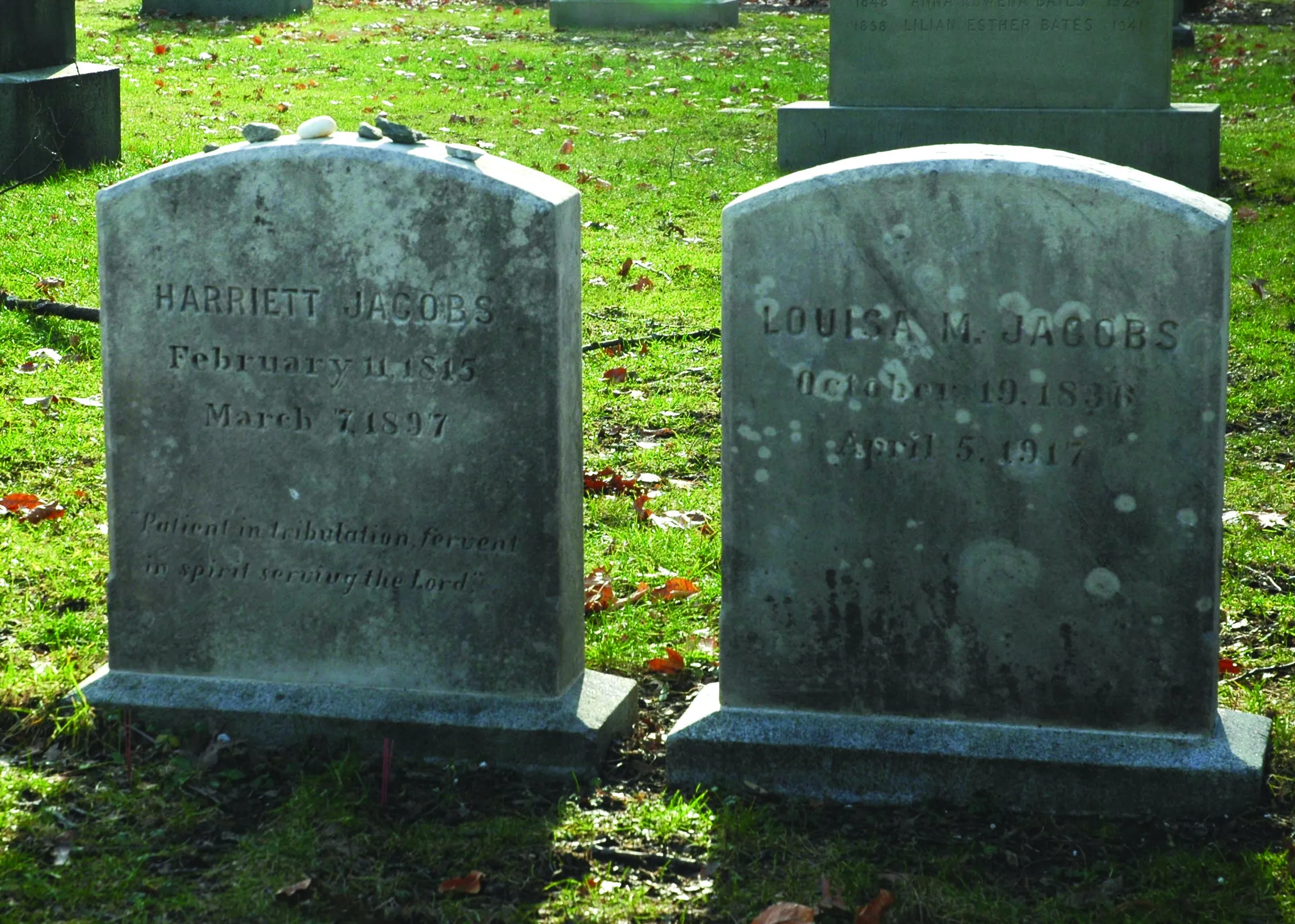 Two gravestones next to each other weathered by the elements.