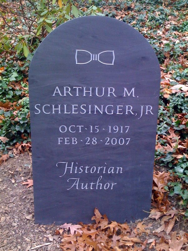 A photograph of a slate gravestone with a bow-tie carved at the top.