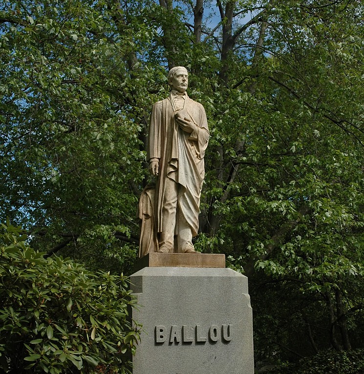 A photograph of a life-size sculpture of a man as a gravestone monument.
