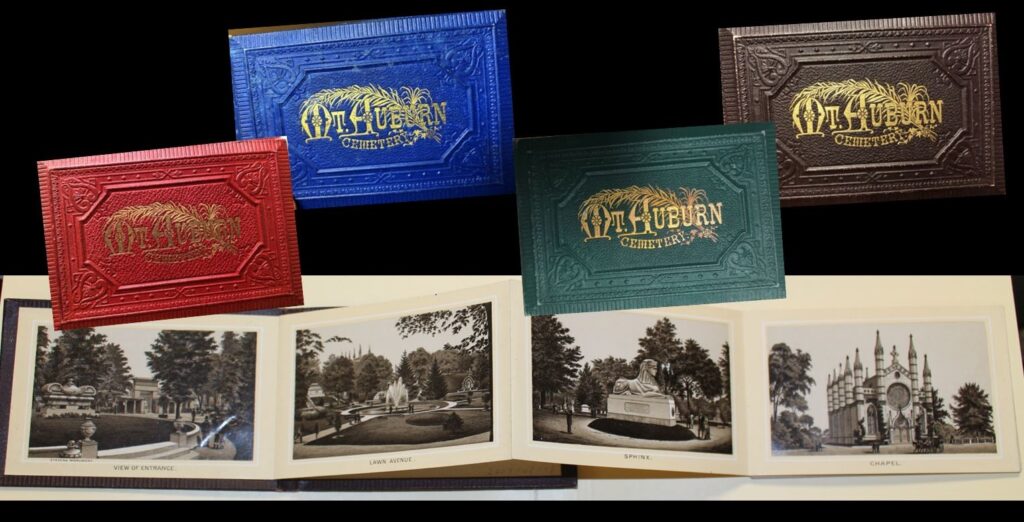 Four small Mt Auburn photo albums, each with a different color cover: red, blue, green, and brown, and one opened album showing four 19th-century cemetery views in sepia, with titles below, on an accordion page.