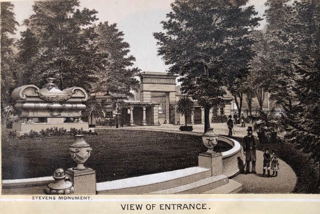 Sepia image of a 19th-century ornamental cemetery entrance with a gateway, large monument, palm trees, mature deciduous trees, curbing, lawn, and visitors strolling on pathways. Below text reads “Stevens monument” and “View of Entrance.”